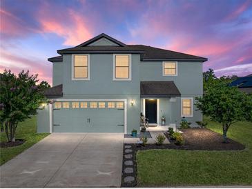 Charming two-story home with a well-manicured lawn, inviting entrance, and attached garage at dusk at 5660 Elsinore Way, Lakeland, FL 33805