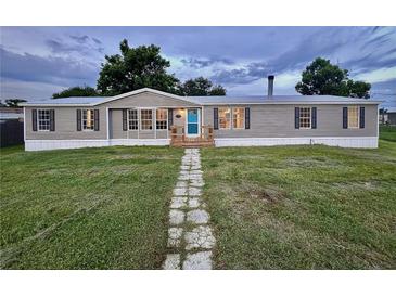 Charming single-story home with gray siding, black shutters, a lush front lawn, and a stone walkway at 5790 Cherry Tree Dr, Lakeland, FL 33811