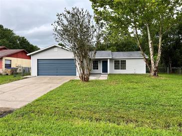 Charming single-story home with a well-manicured lawn, blue garage door, and mature trees at 299 Cobalt Dr, Kissimmee, FL 34758