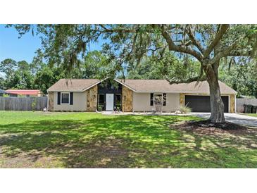 Charming single-story home featuring a stone facade, manicured lawn, and mature trees at 4621 Musket Dr, Lakeland, FL 33810