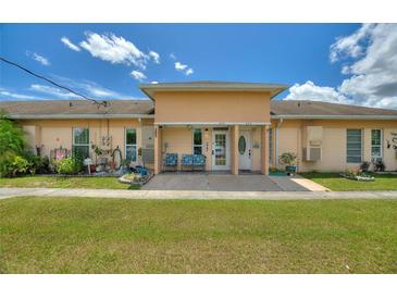 Charming duplex featuring a well-manicured lawn and cozy front porch seating at 523 Club Cir, Lakeshore, FL 33854