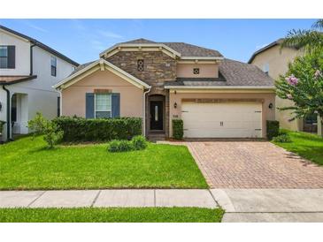 Charming single-Gathering home featuring a stone accent wall, brick driveway, manicured lawn, and a two-car garage at 1138 Fountain Coin Loop, Orlando, FL 32828
