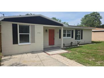Charming single-story home featuring neutral paint, modern shutters, and a welcoming red front door at 1514 Crest Ave, Leesburg, FL 34748