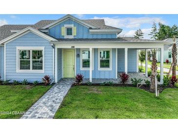 Charming blue home with a welcoming front porch, lush landscaping, and a gray brick walkway at 198 Gypsy Palace Ln, Daytona Beach, FL 32124
