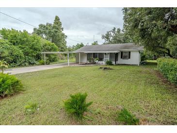 Quaint single story home with mature trees, green lawn and attached carport at 1400 E Fern Rd, Lakeland, FL 33801