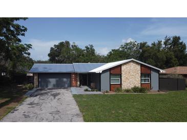 Charming single-story home featuring a blue metal roof, two-car garage, and a well-manicured front lawn at 4041 Se 20Th Ct, Ocala, FL 34480