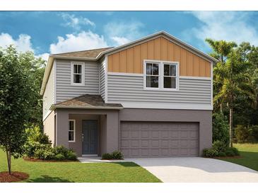 Two-story home featuring neutral gray horizontal siding, a welcoming entrance, and an attached two-car garage at 738 Ambleside Dr, Haines City, FL 33844