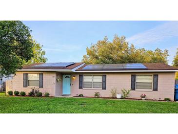 Charming single-story home featuring a welcoming blue door and modern solar panels on the roof at 1841 Talmadge St, Deland, FL 32724