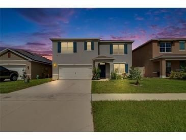 Charming two-story home with a well-manicured lawn, shutters, and a two-car garage against a beautiful dusk sky at 623 Grove St, Winter Haven, FL 33881
