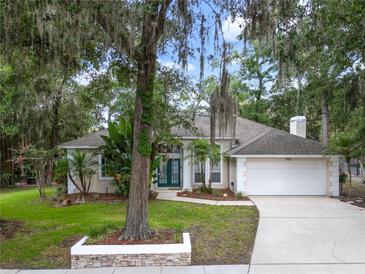 Charming single-story home featuring a two-car garage, manicured lawn, and mature landscaping at 116 Winding Oaks Ln, Oviedo, FL 32765