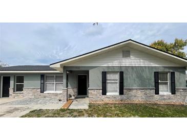 Charming home featuring a stone accent facade, black shutters, and a modern black door at 1420 Wood Ave, Haines City, FL 33844