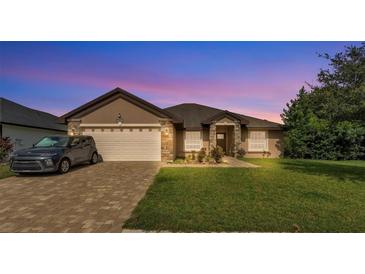 Charming single-story home featuring a brick driveway, a two-car garage, and well-maintained landscaping at 311 Bentley Oaks Blvd, Auburndale, FL 33823