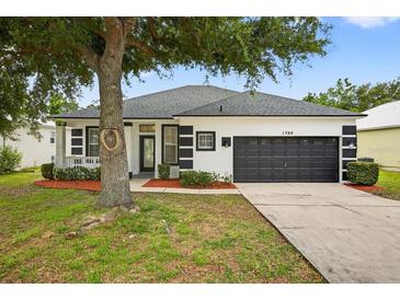 Charming single-story home featuring a two-car garage, landscaped front yard, and inviting entryway at 1760 Mountclair Ct, Mount Dora, FL 32757