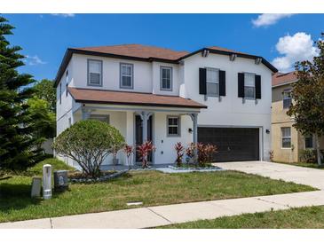 Two-story house with gray and white exterior, two-car garage, and manicured lawn at 233 Rosselli Blvd, Davenport, FL 33896