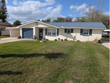 Charming home with blue metal roof and shutters, complemented by a spacious, well-maintained front yard at 1628 Paradise Ln, Astor, FL 32102
