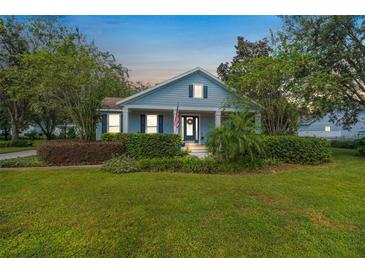 Attractive light blue house with a porch, landscaping, and American flag at 450 W Delaware Ave, Lake Helen, FL 32744