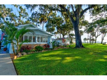 Charming bungalow with a lush front yard, mature trees, and patio at 111 Fleming Ave, Port Orange, FL 32127