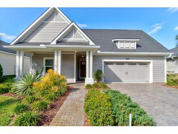 Charming home featuring a manicured front yard, a two-car garage and a welcoming front porch at 112 Chelsea Place Ave, Ormond Beach, FL 32174