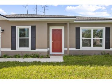 Inviting home featuring a red front door, complemented by black shutters and a well-maintained lawn at 2126 7Th Ave, Deland, FL 32724