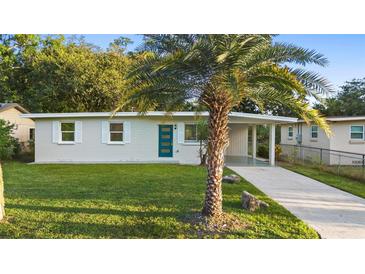 Charming single-story home featuring a well-maintained lawn, a vibrant blue door, and a covered parking area at 522 Powers Ave, Port Orange, FL 32127