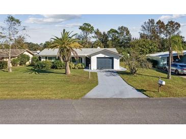 Charming single-story home with a well-manicured lawn, palm tree, and attached garage at 1437 Colin Kelly Ave, Daytona Beach, FL 32124