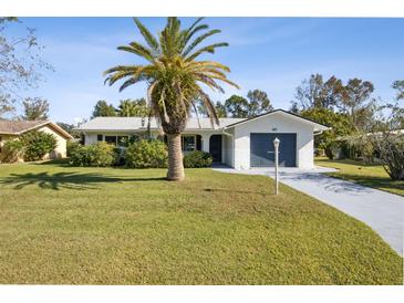 Charming single-story home with a well-manicured lawn, mature palm tree, and a blue two-car garage door at 1437 Colin Kelly Ave, Daytona Beach, FL 32124