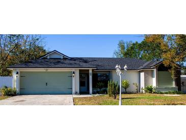 One-story house featuring a light green garage door, a gray roof, and well-manicured lawn at 1083 E Normandy Blvd, Deltona, FL 32725