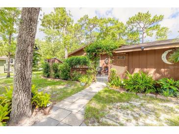 Charming home entrance with a trellised gate, lush greenery, and a stone pathway leading to the front door at 115 Cypress Pond Rd, Port Orange, FL 32128