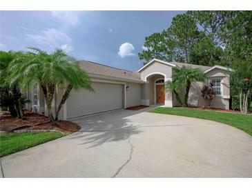 Inviting home featuring a two-car garage, landscaped yard, and elegant entryway with arched alcove at 189 Perfect Dr, Daytona Beach, FL 32124