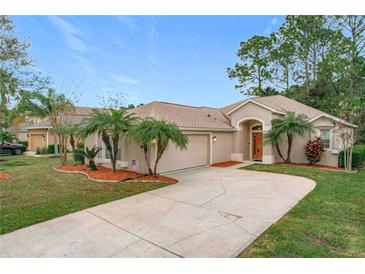 Tan house with palm trees, a two-car garage, and a manicured lawn at 189 Perfect Dr, Daytona Beach, FL 32124