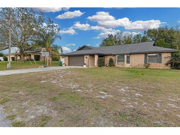 Brick home with a large yard, driveway, and basketball hoop at 1945 Eden Dr, Deltona, FL 32725