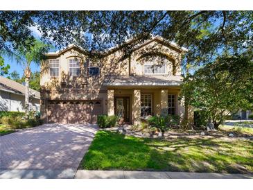 Two-story house with a brick driveway and lush landscaping at 310 Stakes Ct, Deland, FL 32724