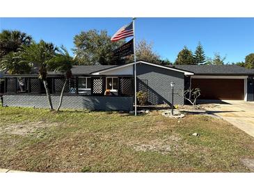Gray brick ranch house with a 2-car garage and American flag at 444 S Deerwood Ave, Orlando, FL 32825