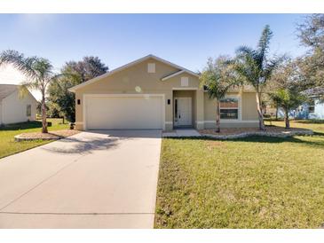 Tan one-story house with a two-car garage and palm trees at 981 Wilmington Dr, Deltona, FL 32725