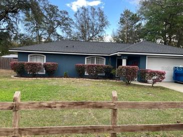 Ranch style home with blue exterior, well-manicured lawn, and wooden fence at 1615 18Th St, Orange City, FL 32763