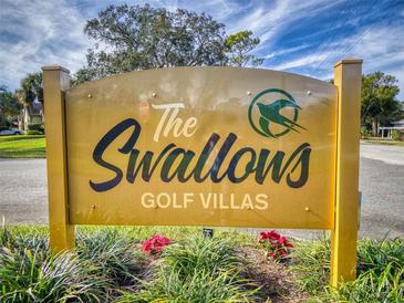 The Swallows Golf Villas entrance sign with vibrant flowers, blue sky, and wispy clouds at 55 Fairway Dr # 3D, Debary, FL 32713