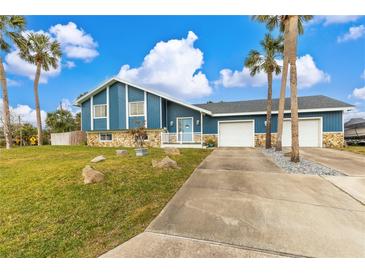 A charming blue house with a two-car garage and palm trees at 63 St Anne Cir, Ormond Beach, FL 32176