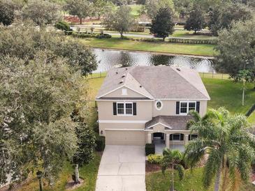 Two-story house with a two-car garage, situated on a tree-lined street near a lake at 10025 Scottish Pines Ct, Orlando, FL 32832