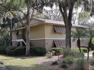 Tan two-story building with brown roof and shutters, nestled among lush greenery at 130 Jasmine Woods Ct # 15C, Deltona, FL 32725