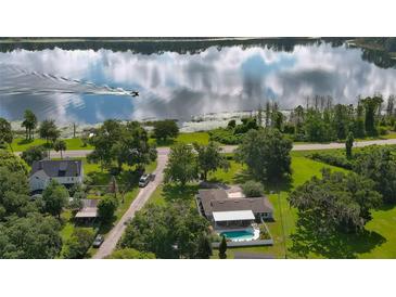 Aerial view of a home with pool, lakefront access, and lush landscaping at 2530 E New York Ave, Deland, FL 32724