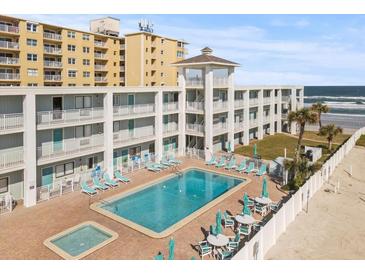 Oceanfront building with pool, patio furniture, and beach access at 3509 S Atlantic Ave # 208, New Smyrna Beach, FL 32169