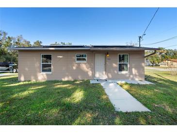 Tan single story house with a walkway, lawn, and solar panels on the roof at 501 W Lisbon Pkwy, Deland, FL 32720