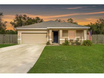Beige house with a two-car garage and a well-manicured lawn at 304 Gardenia Ave, Debary, FL 32713