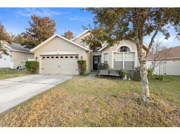 Tan house with a two-car garage and a well-maintained lawn at 3125 Wood Rose Way, Deltona, FL 32725