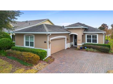 Tan single-story house with a paved driveway and lush landscaping at 1105 Gardenshire Ln, Deland, FL 32724