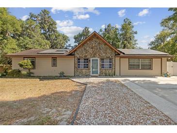 Charming single-story home boasts stone accents, solar panels, and a concrete driveway with decorative gravel walkway at 1240 W Voorhis Ave, Deland, FL 32720