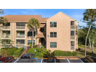 Three-story condo building with tan facade, balconies, palm trees, and convenient parking at 1401 S Palmetto Ave # 614, Daytona Beach, FL 32114