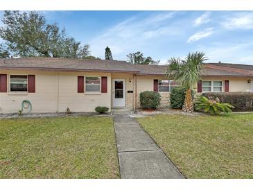 Tan single-story house with a walkway, palm trees, and manicured lawn at 2 Villa Villar Ct # 02, Deland, FL 32724