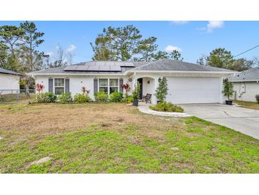 White house with solar panels, landscaped yard, and a two-car garage at 216 Hickory Ave, Orange City, FL 32763