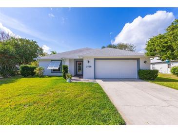 Single-story home with white exterior, attached garage, and well-manicured lawn at 2758 Turnbull Cove Dr, New Smyrna Beach, FL 32168